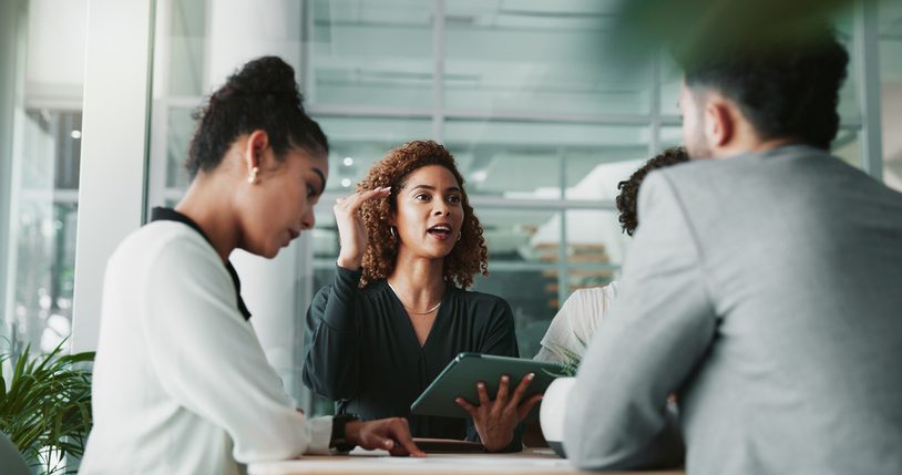 A woman leads a discussion with colleagues in a modern office.