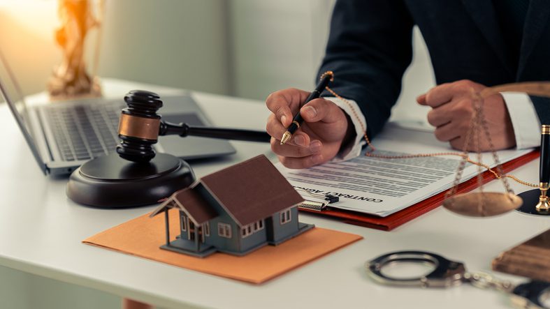 Legal professional reviewing real estate documents with a gavel and model house.